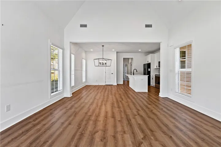 A well-lit, open-concept living space with warm wood flooring seamlessly connecting to the modern kitchen.