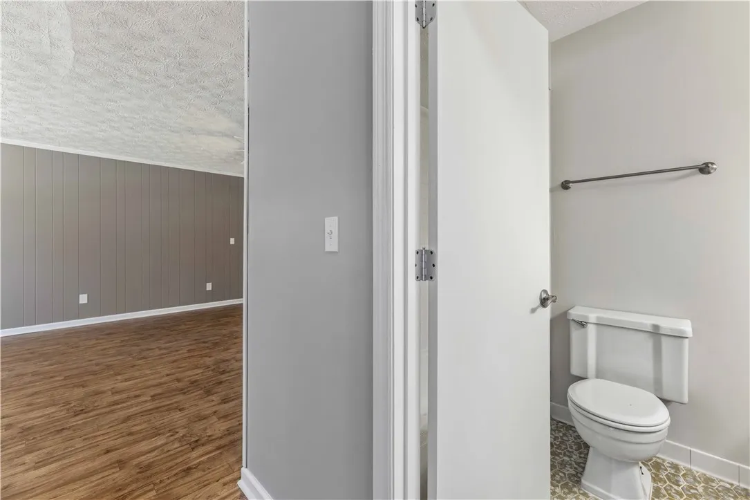 Clean and functional bathroom with wood plank flooring extending to adjacent living space.