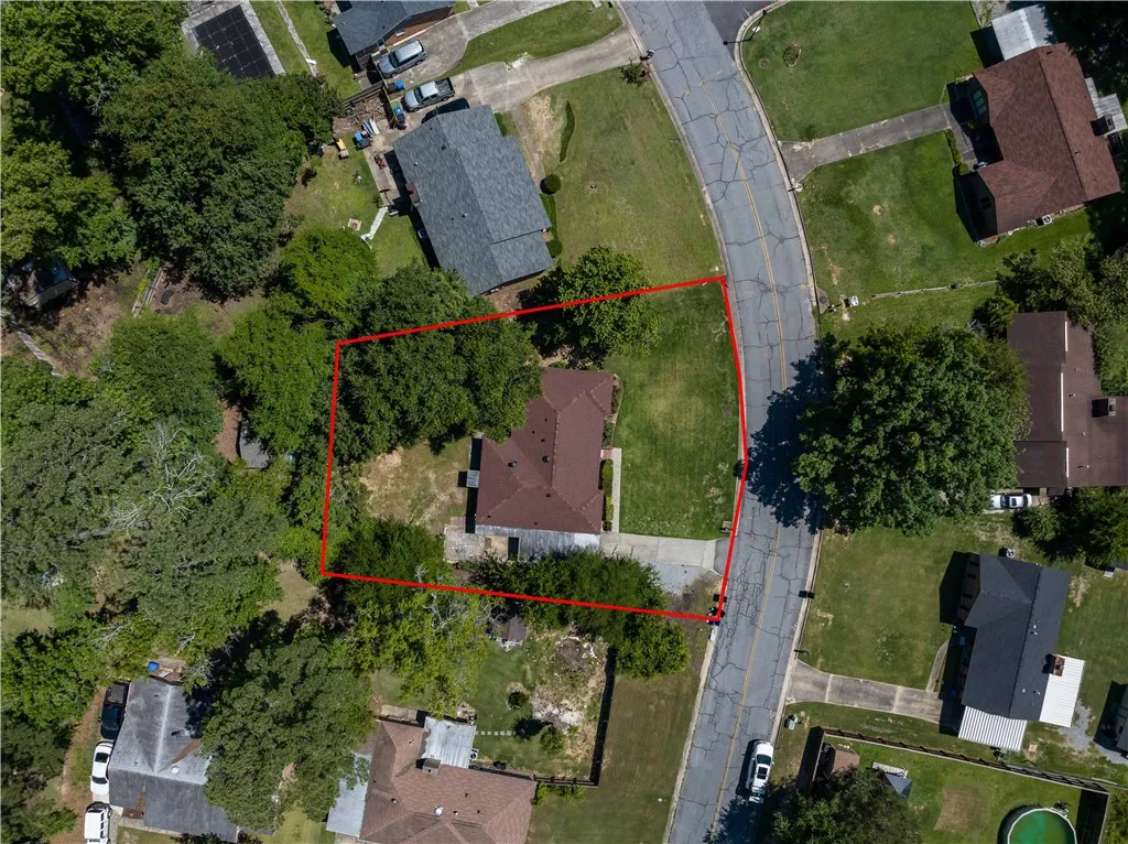 An aerial perspective reveals a private residence nestled amidst mature trees with a well-maintained lawn.