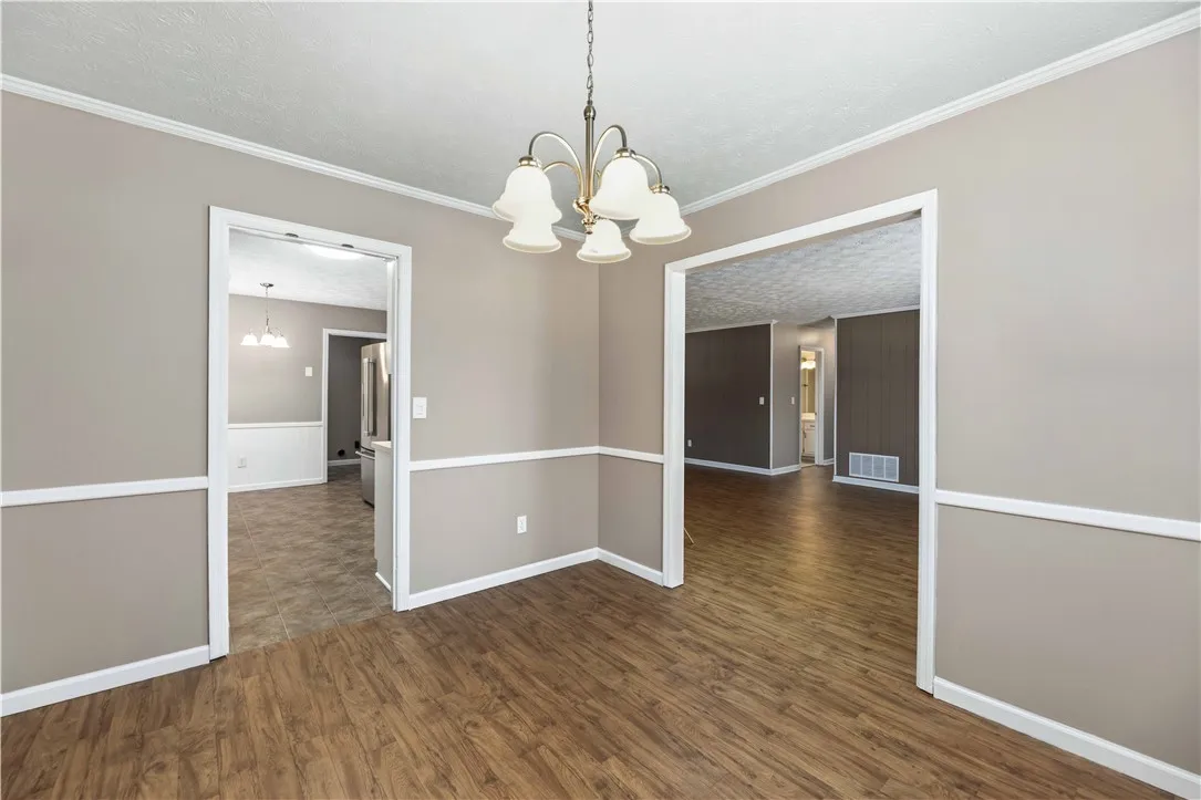 A classic chandelier illuminates the open concept dining space, showcasing rich wood-look flooring.