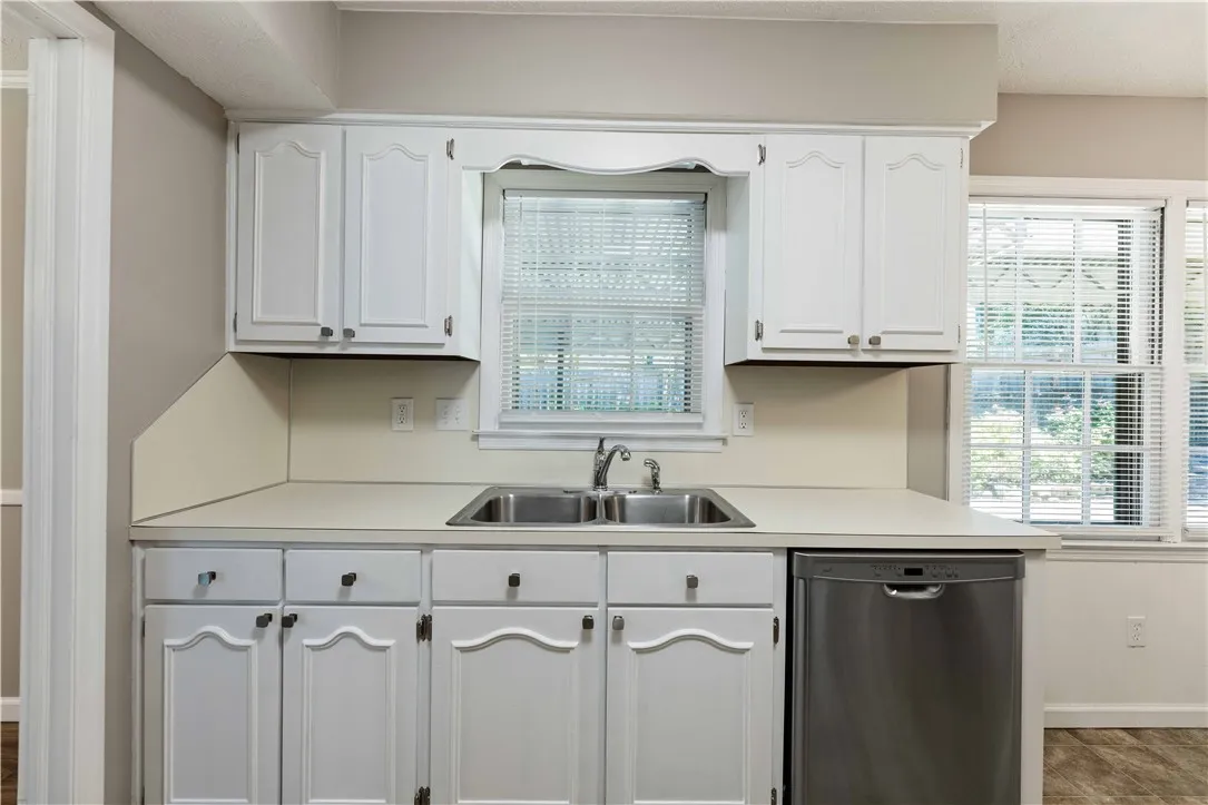 A well-lit kitchen featuring clean white cabinetry, a dual basin sink, and ample countertop space.