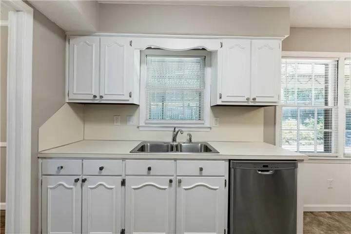 A well-lit kitchen featuring clean white cabinetry, a dual basin sink, and ample countertop space.