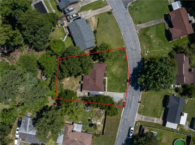 An aerial perspective reveals a private residence nestled amidst mature trees with a well-maintained lawn.