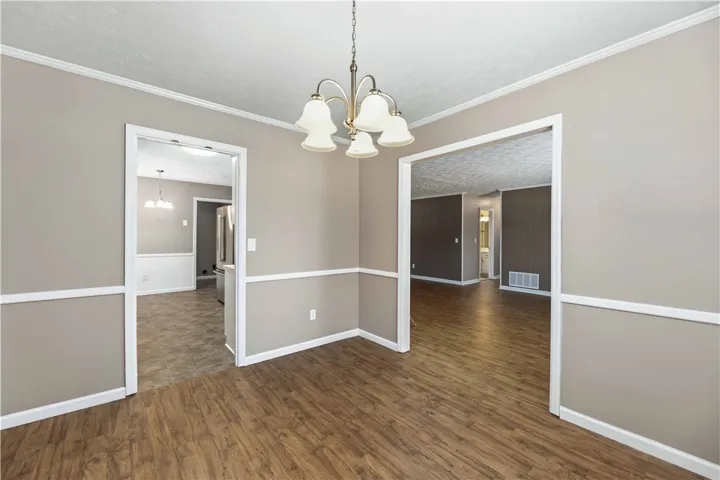 A classic chandelier illuminates the open concept dining space, showcasing rich wood-look flooring.