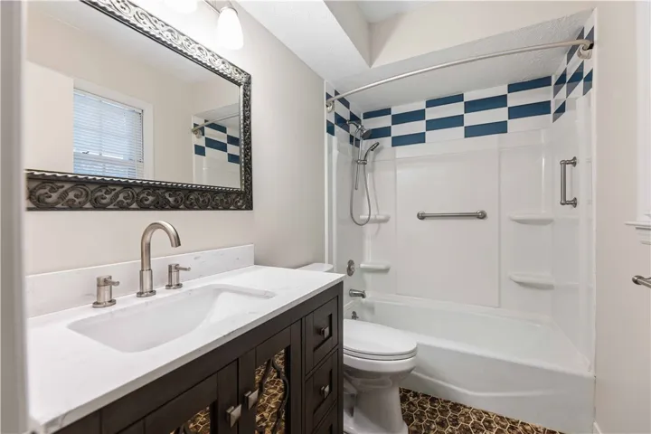A well-appointed bath features a tiled floor, a vanity with a white countertop, and a shower with a decorative tile pattern.