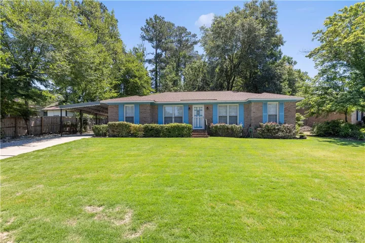 Well-maintained brick exterior residence with a welcoming front yard and mature trees.