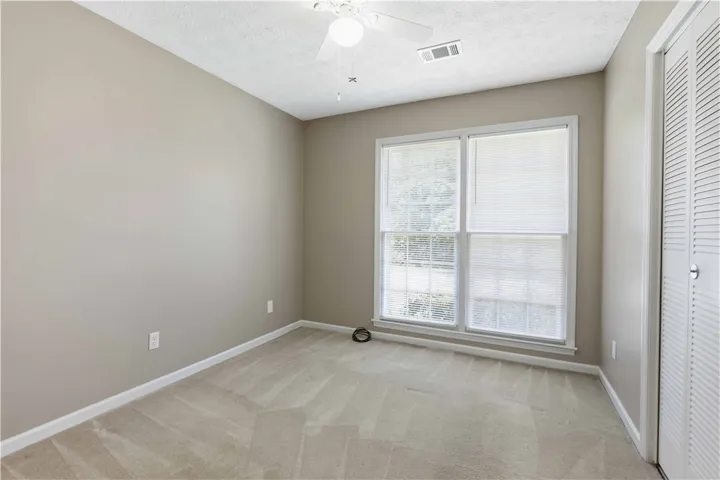 A well-lit room featuring neutral tones and a practical ceiling fan.