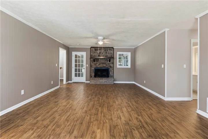 A spacious common area showcases rich hardwood flooring and a stone-clad fireplace.