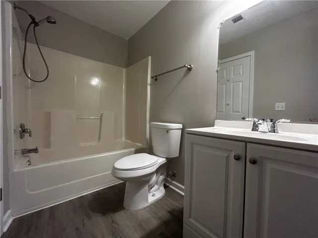 A well-lit bathroom features a functional shower and bathtub combination alongside a pristine vanity.