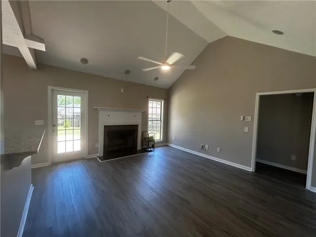 A spacious living area featuring vaulted ceilings and a classic fireplace.