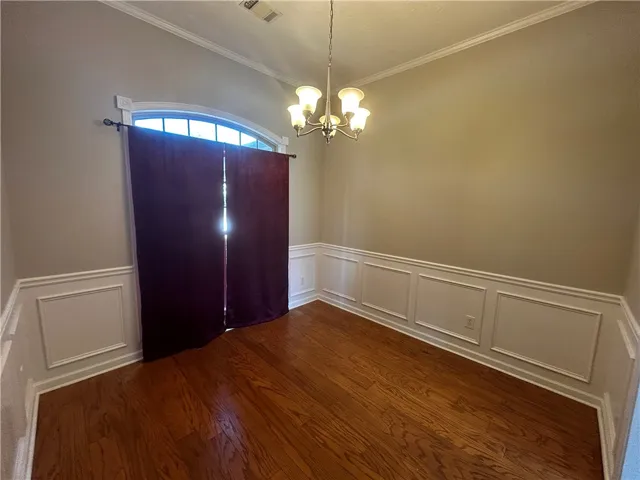 Elegant hardwood flooring grounds a refined dining room, accented by decorative chair rail molding and crown molding.