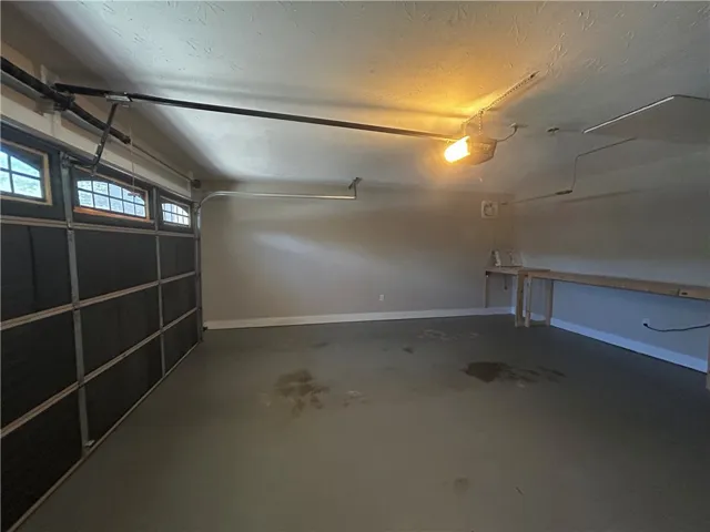 A spacious garage featuring a work bench and ample room for vehicles.