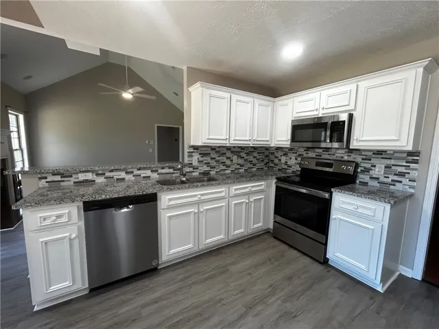 A well-appointed kitchen showcasing elegant white cabinetry, sleek stainless steel appliances, and durable granite countertops.