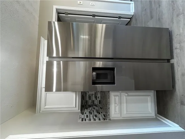 A sleek stainless steel refrigerator anchors this thoughtfully designed kitchen, complete with a mosaic tile backsplash.