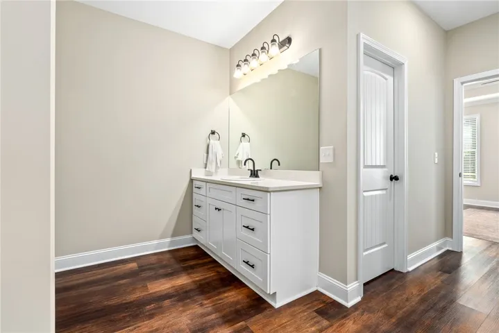 A refined bathroom featuring rich wood-look flooring and a modern dual vanity with stylish hardware.