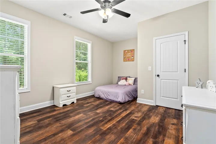 Rich hardwood floors complement a neutral palette, creating a serene bedroom atmosphere.