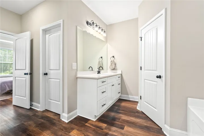 Rich hardwood floors complement a pristine white vanity with ample storage in this well-appointed​​‌​​​​‌​​‌‌​‌‌​​​‌‌​‌​‌​‌​​​‌​​ bathroom.
