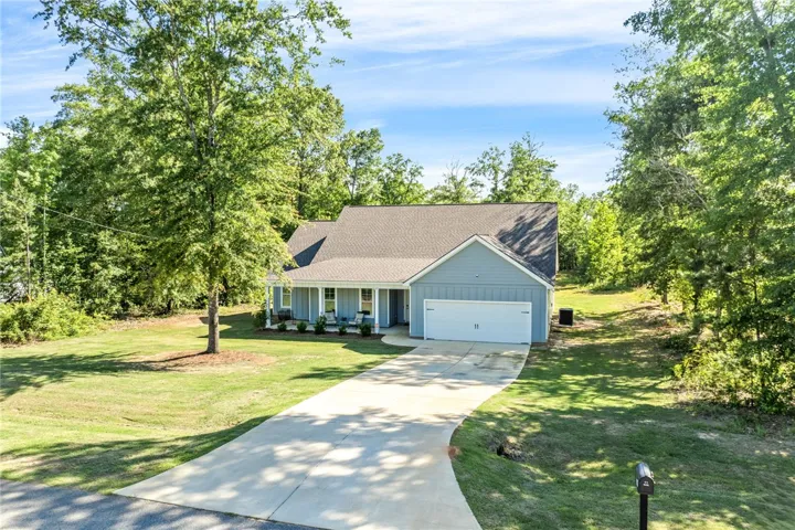 A welcoming abode nestled amongst mature trees, featuring a concrete driveway and an inviting front porch.