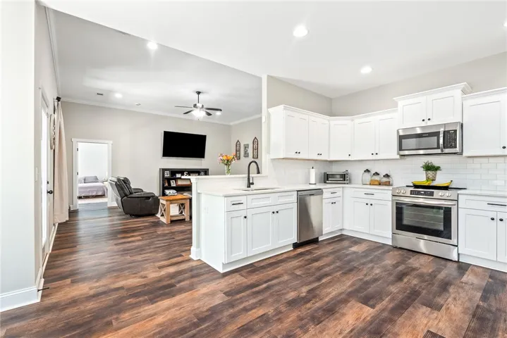 A streamlined kitchen with white cabinetry and stainless steel appliances flows seamlessly into the living space.