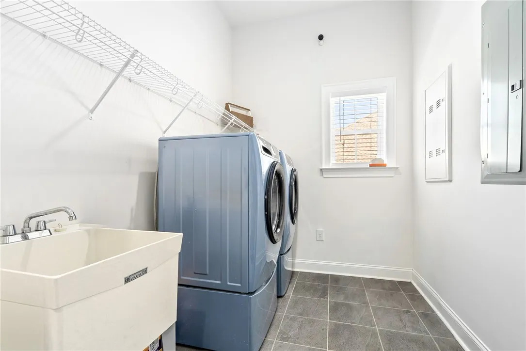 Functional utility space with durable tile flooring and convenient laundry appliances.
