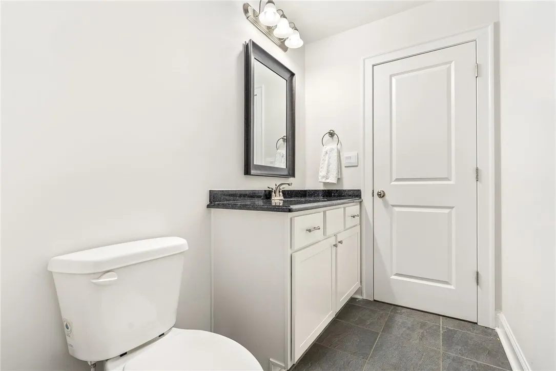 A well-maintained lavatory featuring a vanity with dark counters and tiled​​‌​​​​‌​​‌‌​‌‌​​​‌‌​‌​‌​‌​​​‌​​ flooring.