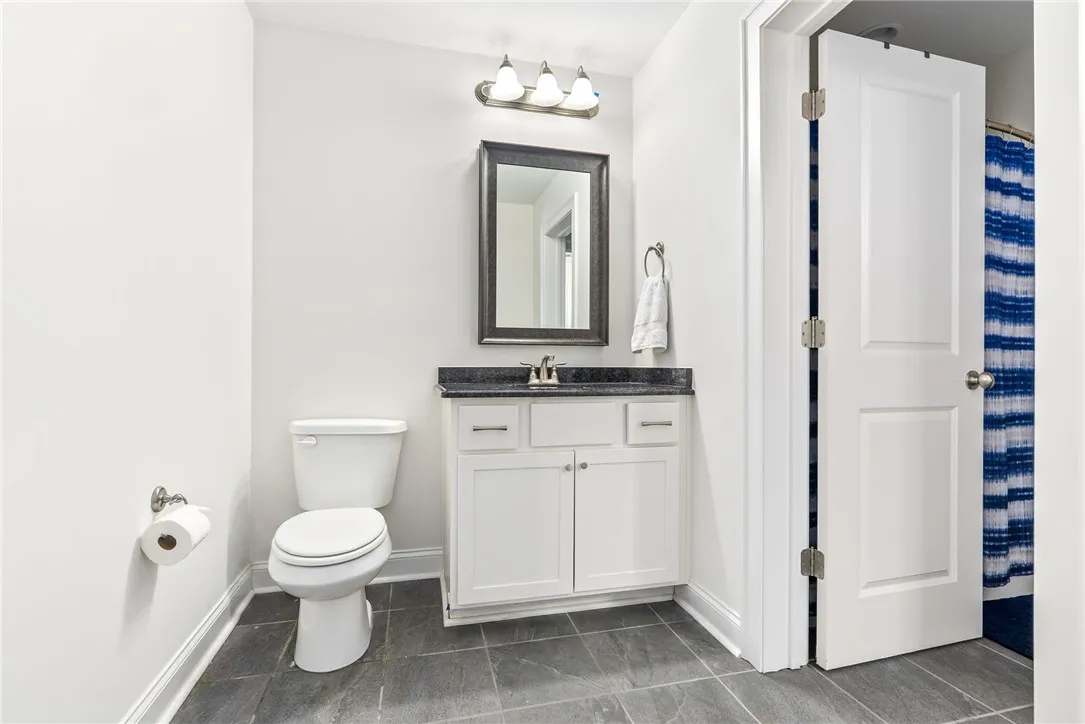 A pristine bathroom features a single vanity, a toilet, and gray tile flooring.