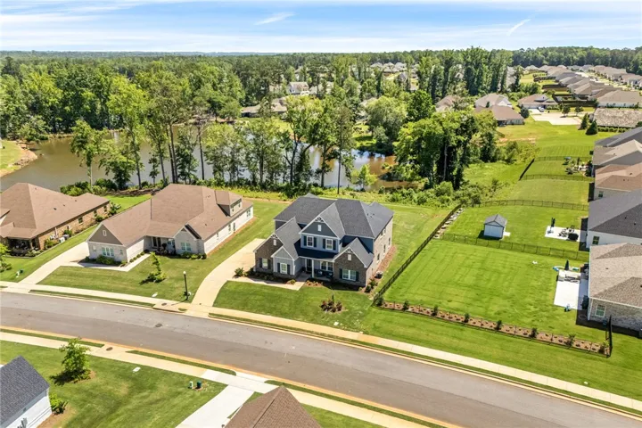 An aerial perspective reveals two-story architecture and a lush yard backing onto a serene pond.
