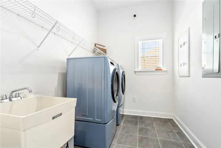 Functional utility space with durable tile flooring and convenient laundry appliances.