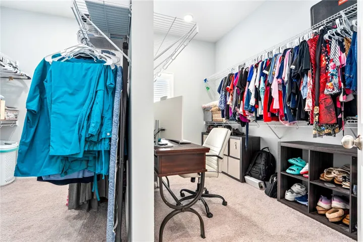 Well-lit primary walk-in closet with ample storage and built-in shelving.