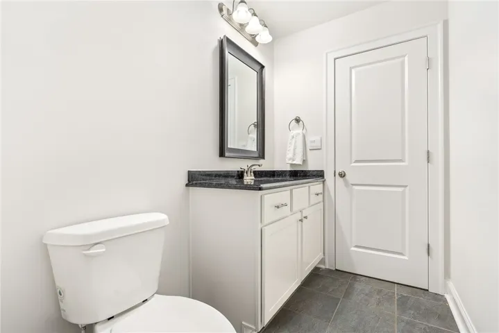 A well-maintained lavatory featuring a vanity with dark counters and tiled​​‌​​​​‌​​‌‌​‌‌​​​‌‌​‌​‌​‌​​​‌​​ flooring.