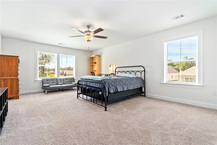 Well-lit sleeping quarters with a ceiling fan, abundant natural light, and plush carpeting for comfort.