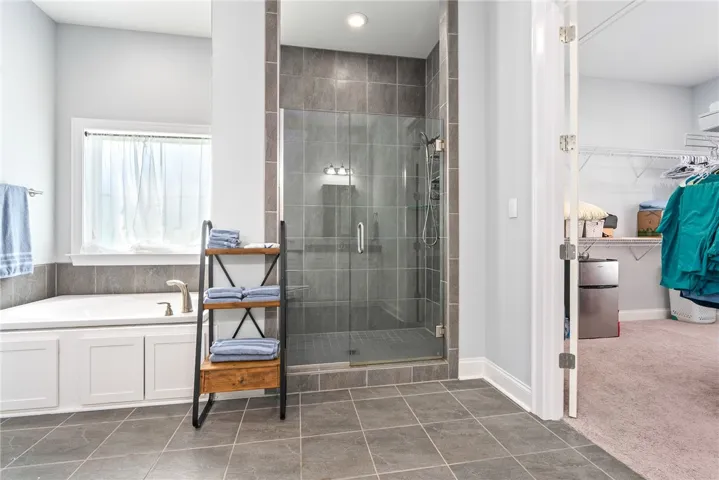 A spacious primary bathroom boasts a relaxing soaking tub and a sleek, glass-enclosed shower.