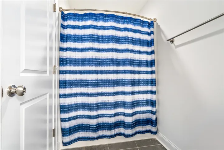 A well-lit shower area features a curved rod and a vibrant blue and white striped curtain.