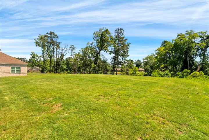 A spacious green lawn extends to a pond, offering abundant natural surroundings and peaceful vistas.
