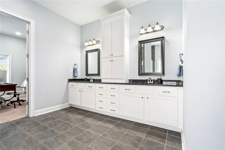 A well-appointed primary bathroom features a double vanity with ample storage and stone counters.