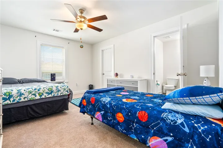 A well-lit bedroom features plush carpeting and a convenient en-suite bathroom.