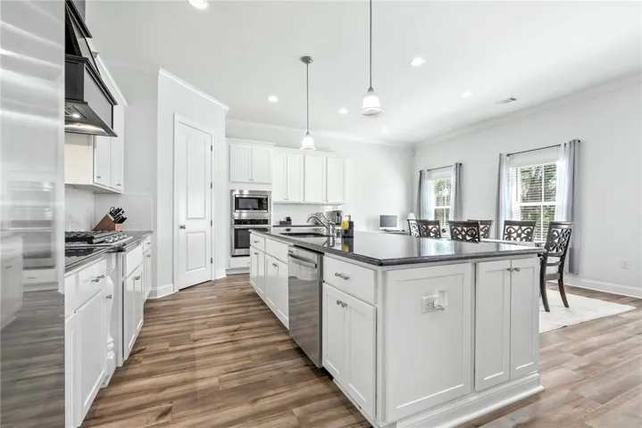 A well-appointed kitchen features a central island, recessed lighting, and rich wood flooring.