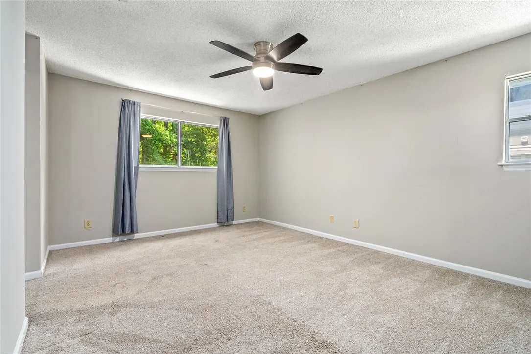 A quiet bedroom offering lush outdoor views and comfortable carpeting.
