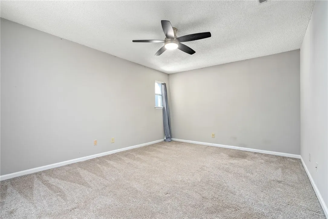 A quiet bedroom offers plush carpeting and a modern ceiling fan, perfect for a peaceful retreat.