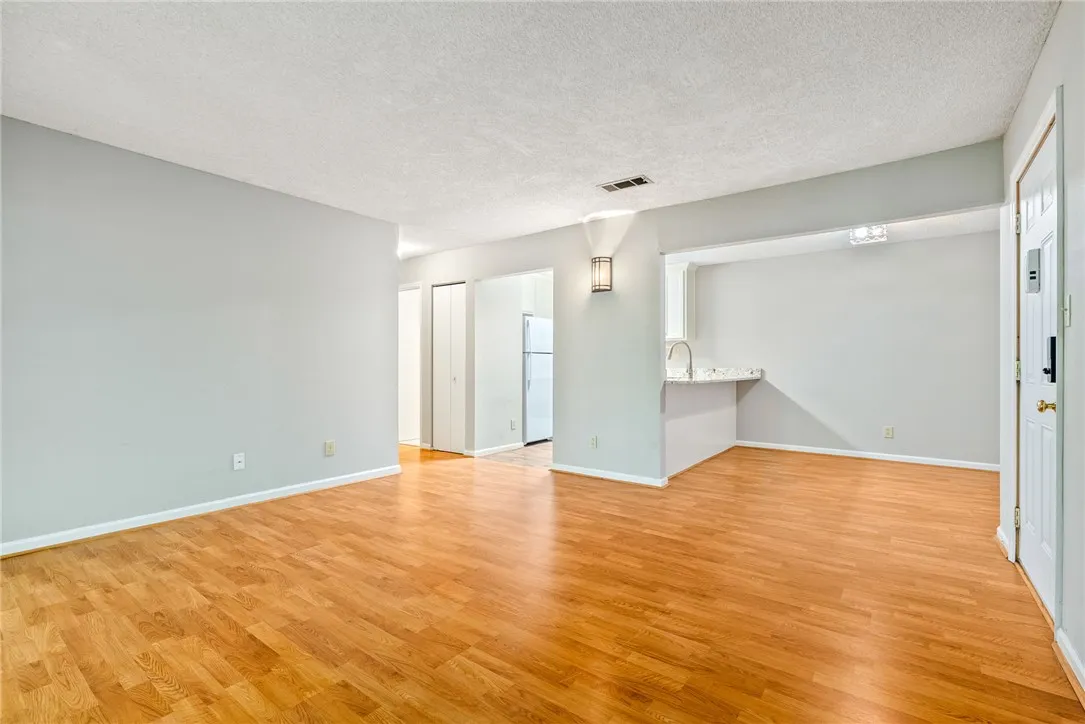 A well-lit, open-concept living space with lustrous hardwood-style flooring, ready for your personalized touch.