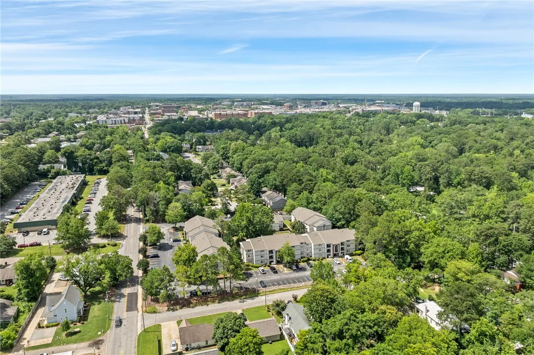 An aerial perspective reveals a verdant suburban landscape with residential and commercial structures nestled amongst a dense tree canopy.