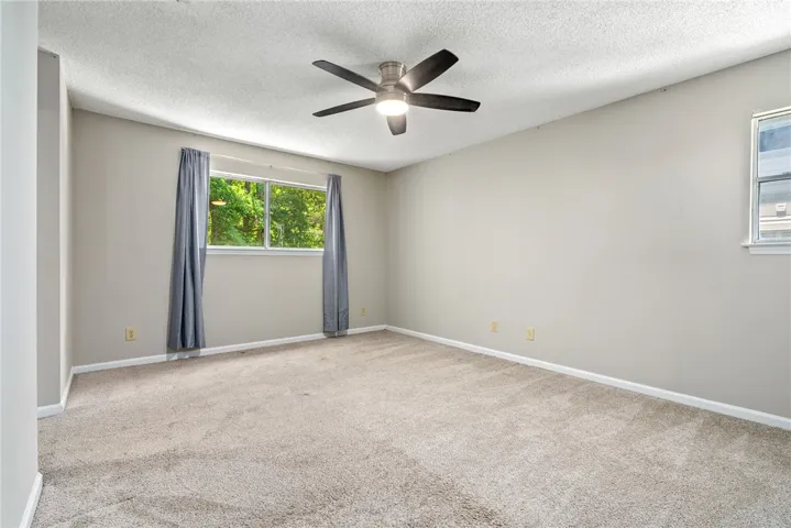 A quiet bedroom offering lush outdoor views and comfortable carpeting.