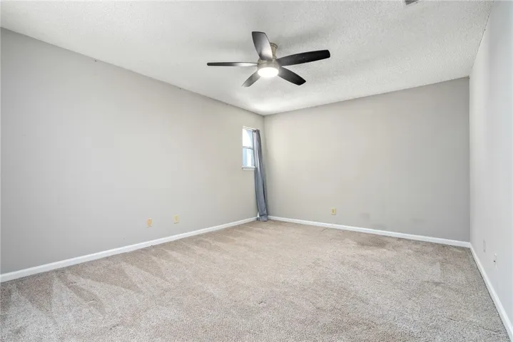 A quiet bedroom offers plush carpeting and a modern ceiling fan, perfect for a peaceful retreat.