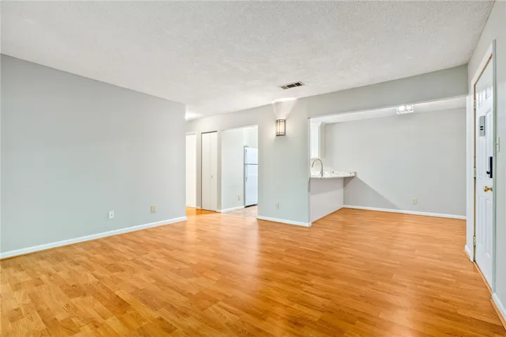 A well-lit, open-concept living space with lustrous hardwood-style flooring, ready for your personalized touch.