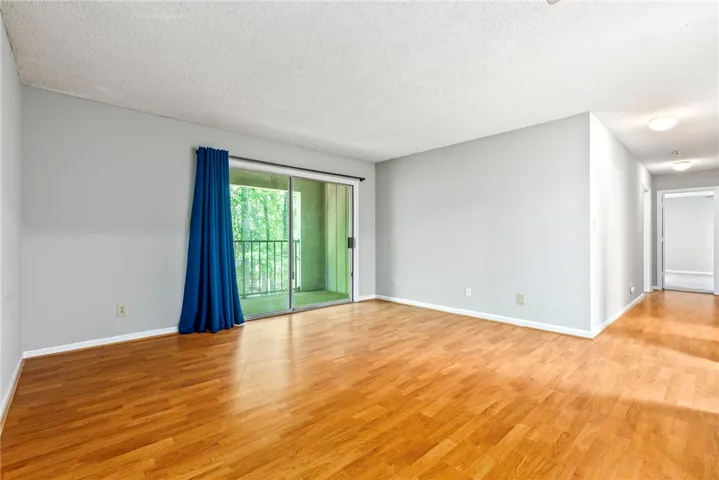 Hardwood flooring extends throughout this generous living space, leading to a private balcony with serene views.