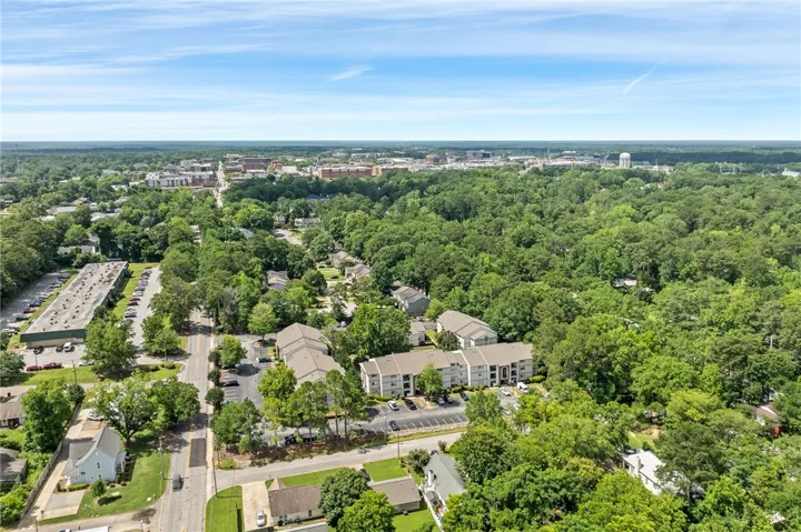 An aerial perspective reveals a verdant suburban landscape with residential and commercial structures nestled amongst a dense tree canopy.