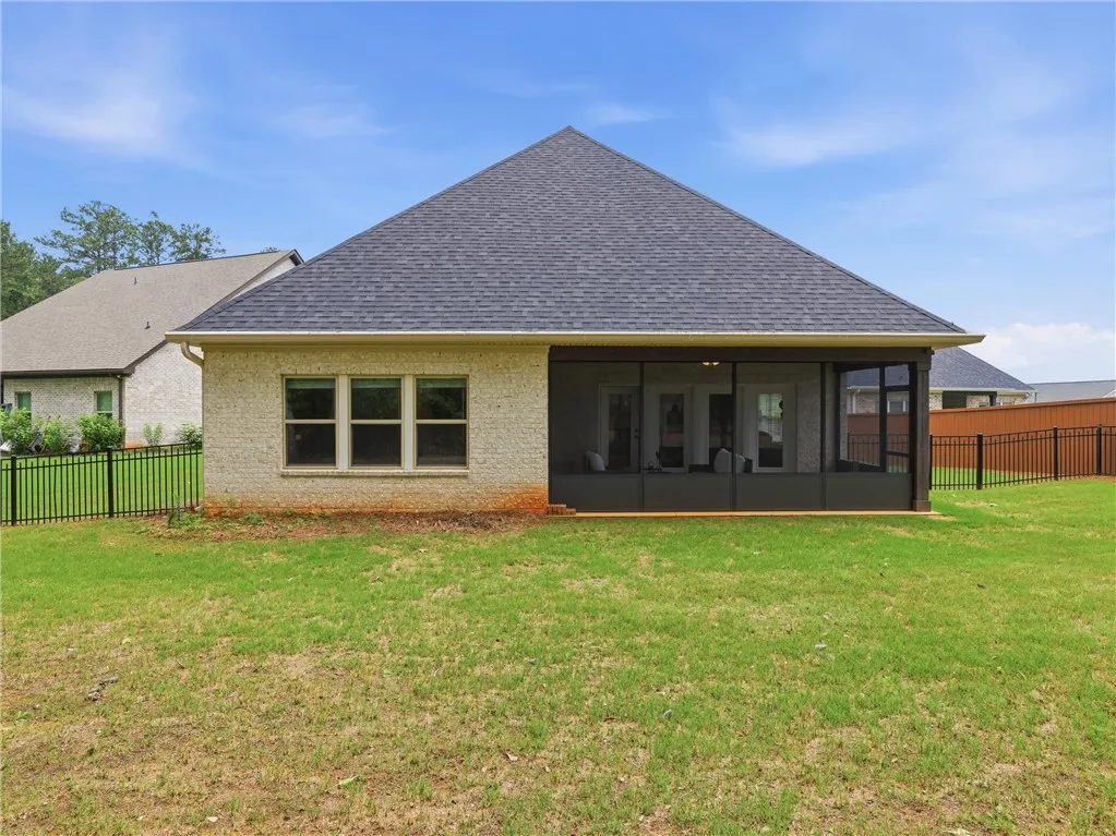 A well-maintained lawn stretches to a brick home featuring a screened-in porch, ideal for enjoying the outdoors.