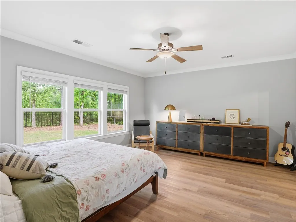 Natural light floods this inviting primary bedroom through a bank of generous windows.