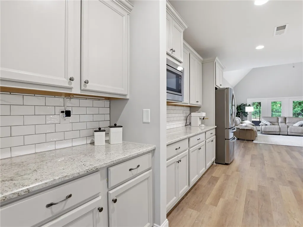 Granite counters and subway tile backsplash elevate this inviting kitchen, flowing into a comfortable living area.