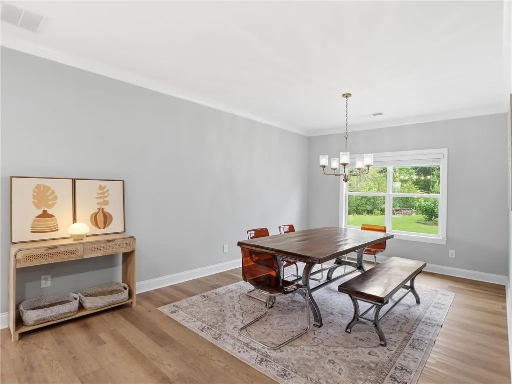Elegant crown molding highlights this bright dining area, featuring beautiful hardwood flooring and a stylish light fixture.